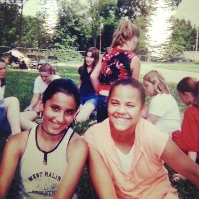 Liz and Annika as teenagers, sitting on the grass at a park